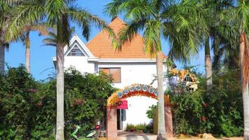 A building with a red-tiled roof, surrounded by palm trees, and a decorative archway at the entrance.
