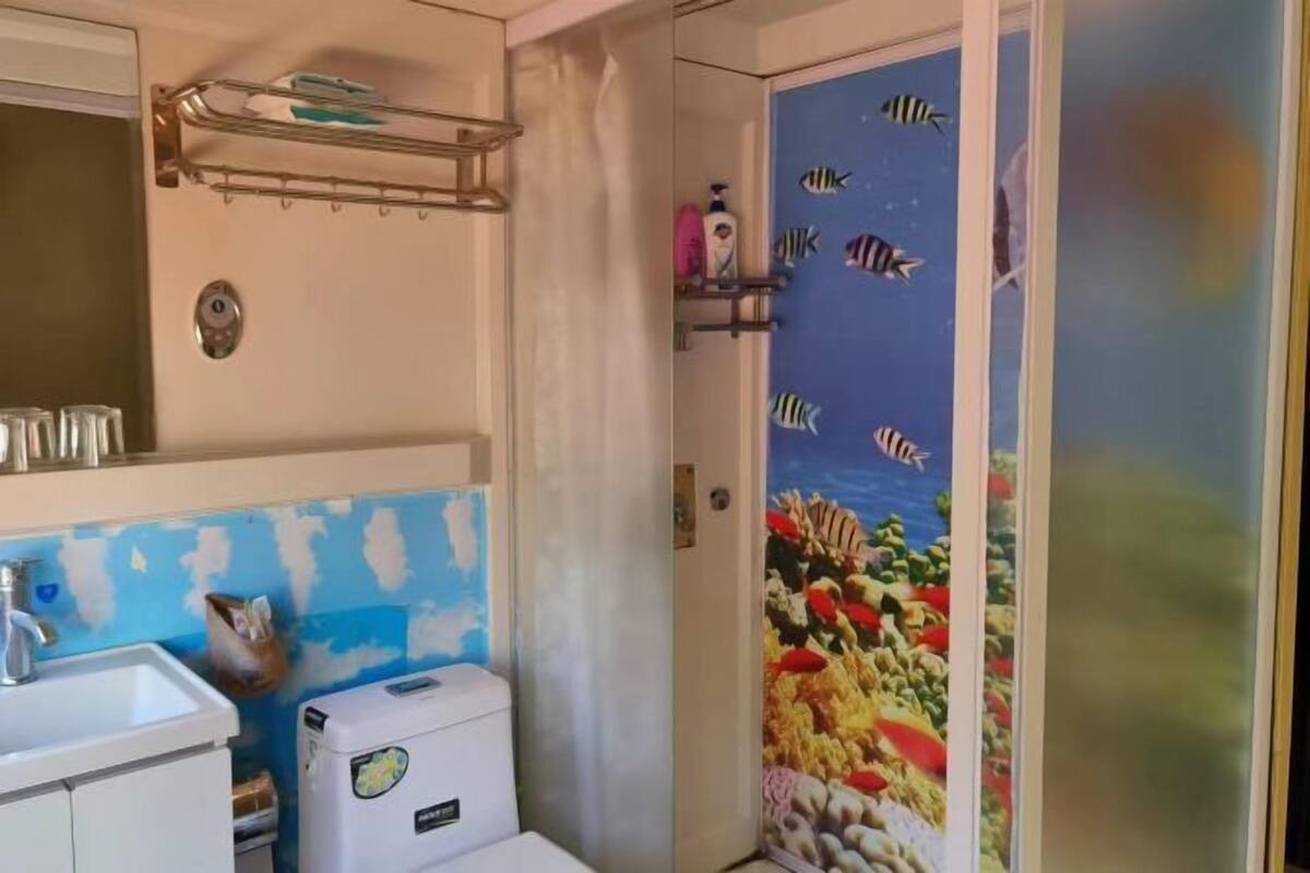 A bathroom with a sink, toilet, and a shower with a fish mural.