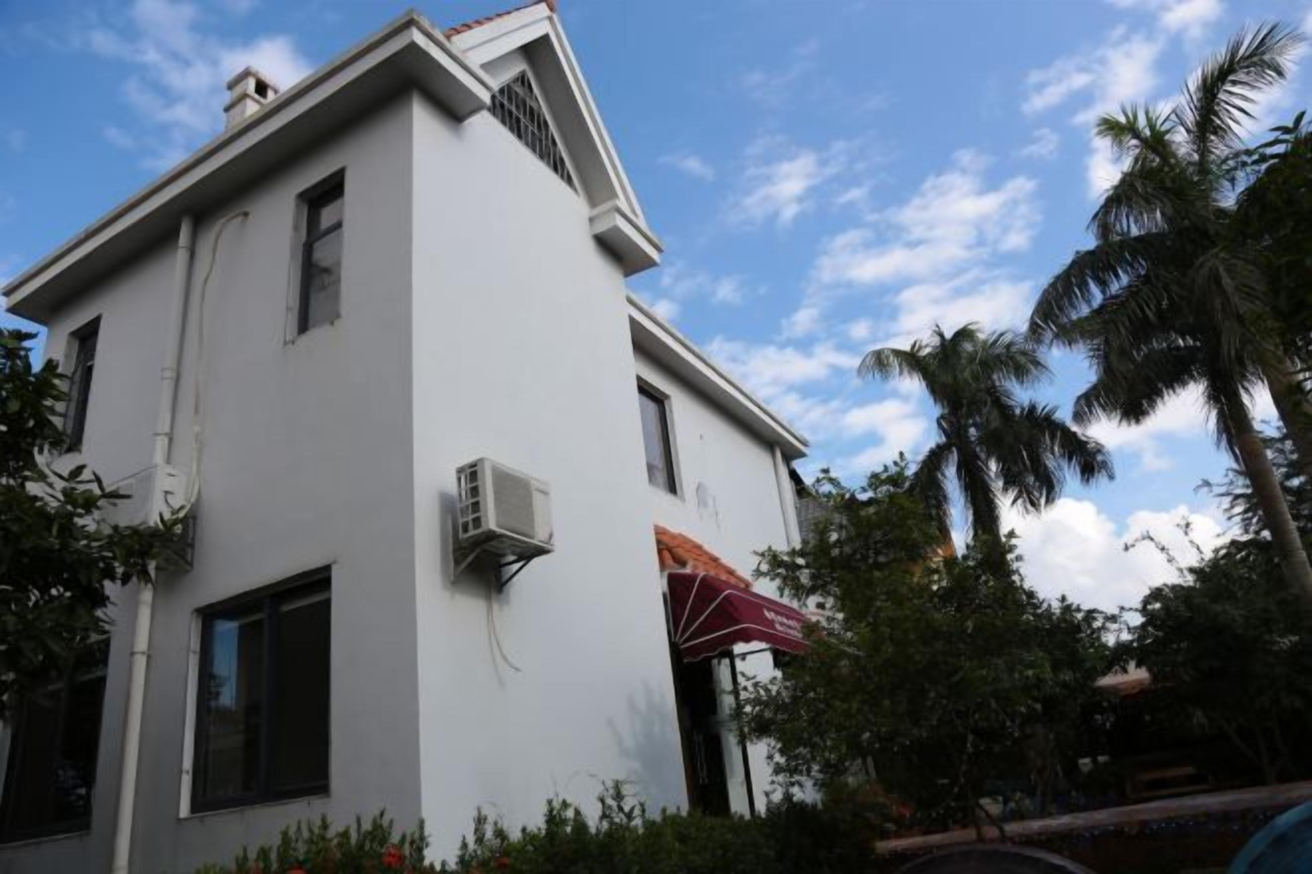 A white building with a flat roof, an air conditioning unit, and a red umbrella.