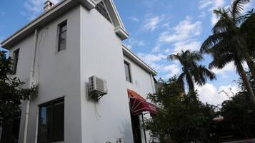 A white building with a flat roof, an air conditioning unit, and a red umbrella.