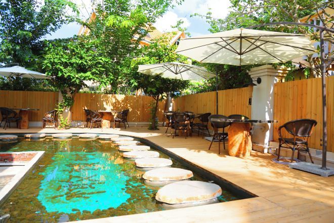 An outdoor patio with a pool, umbrellas, and seating.