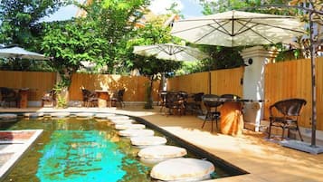An outdoor patio with a pool, umbrellas, and seating.