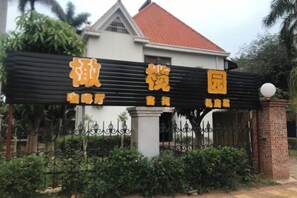 A sign with Chinese characters, a gated entrance, and a building with a red roof. - Olive Tree Coffee Inn (Haikou)