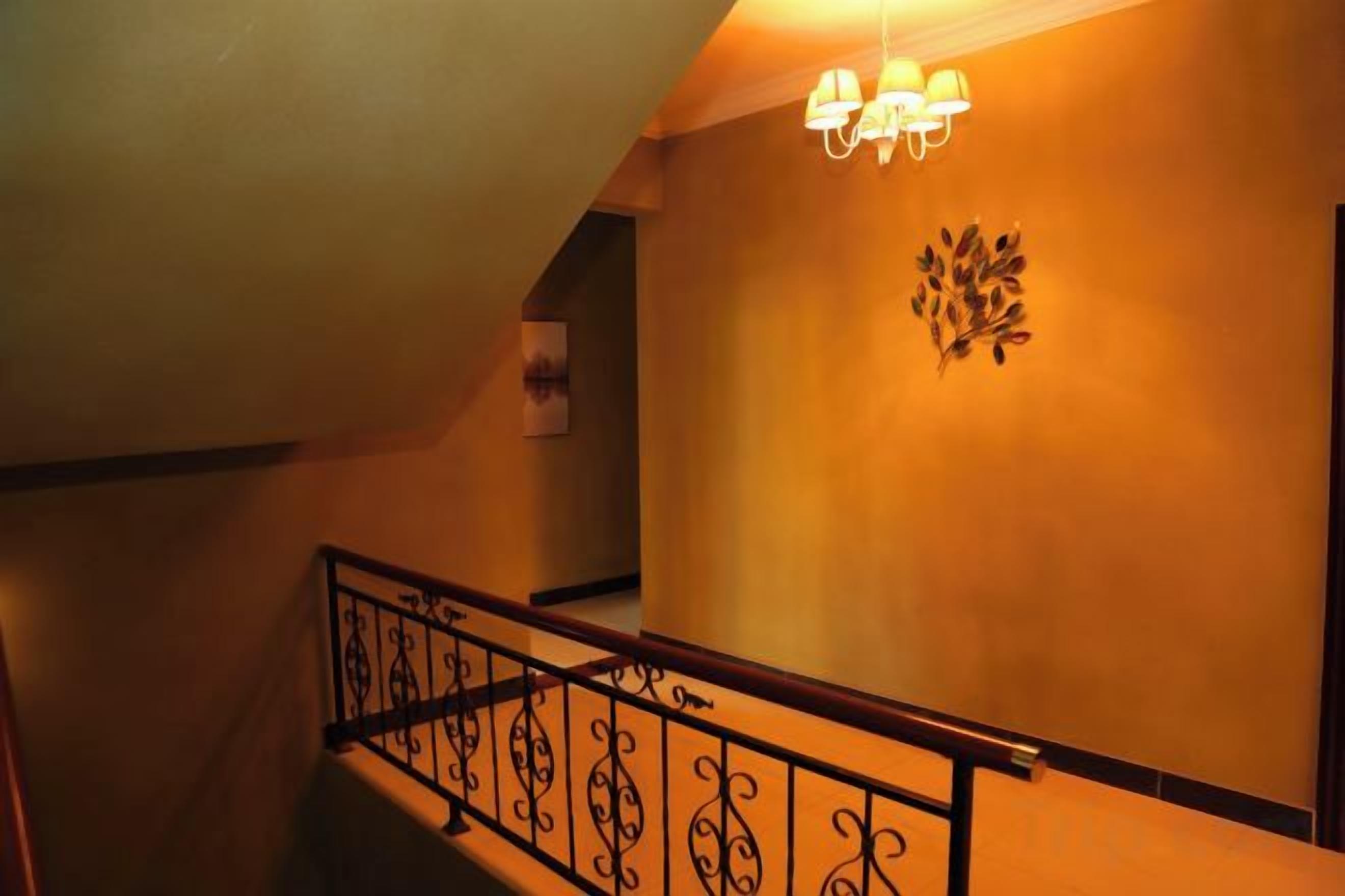 Una scala con ringhiera in ferro battuto, un punto luce a parete e un elemento decorativo.