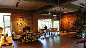 A spacious room with a fireplace, wooden flooring, and a seating area with chairs and a table.