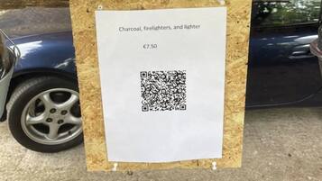 Een houten tafel met twee emmers houtskool, aanmaakblokjes en een aansteker erbovenop, en een prijskaartje van €7,50.
