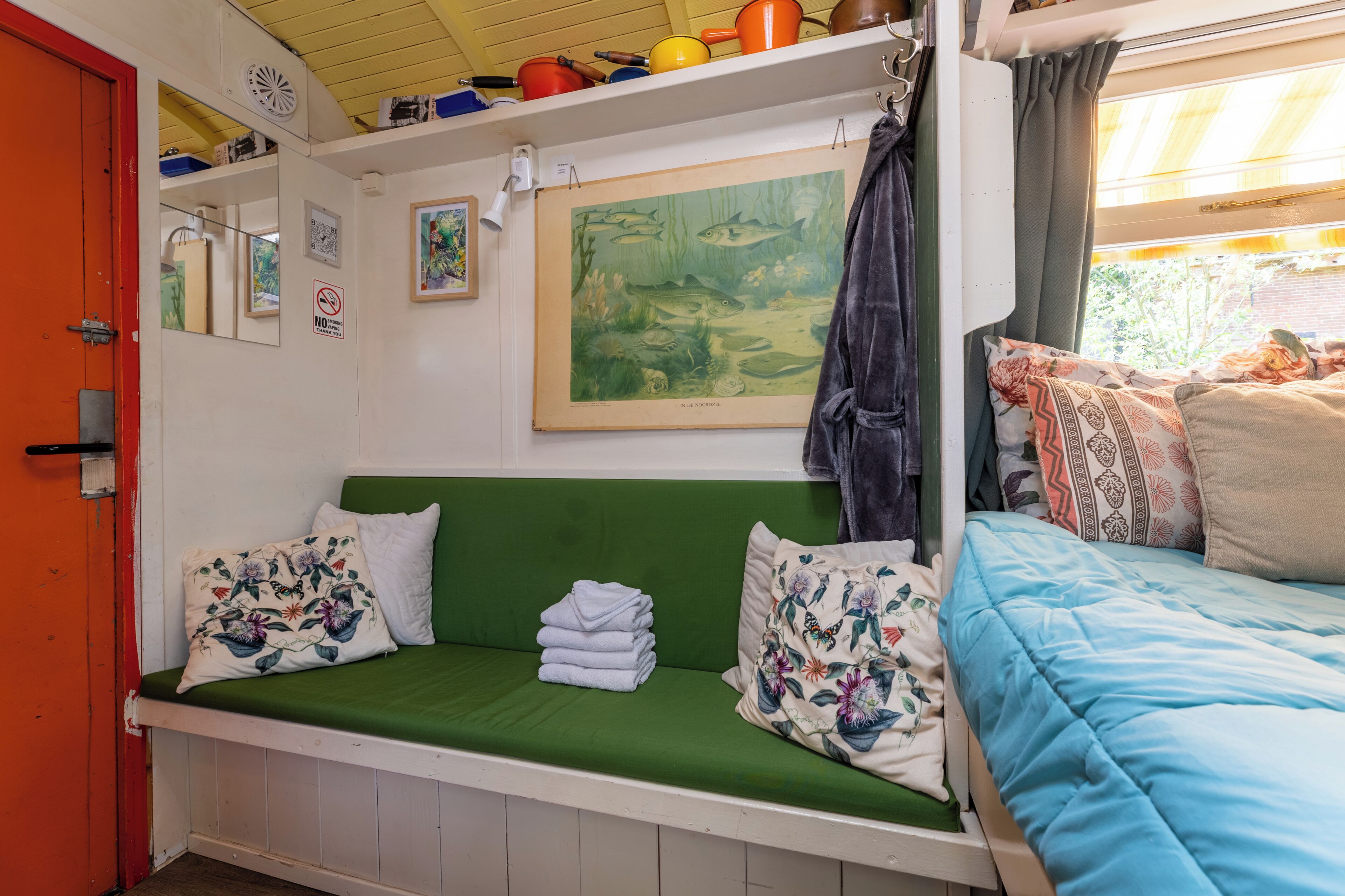 Een gezellige kamer met een groene bank, een blauw bed en een schilderij van vissen aan de muur.