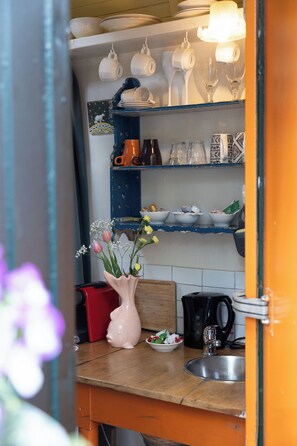 A kitchen with shelves holding various dishes and a vase with flowers.