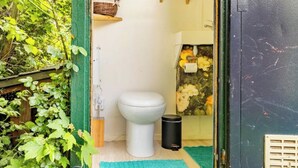 A compact, rustic bathroom with a toilet, a small sink, and a mirror.