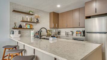A modern kitchen with a large island, wooden cabinets, and stainless steel appliances.