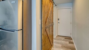 A hallway with a wooden door, a refrigerator, and a light switch on the wall. - Ski Retreat w/ Hot Tub Access in Winter Park! (Winter Park)
