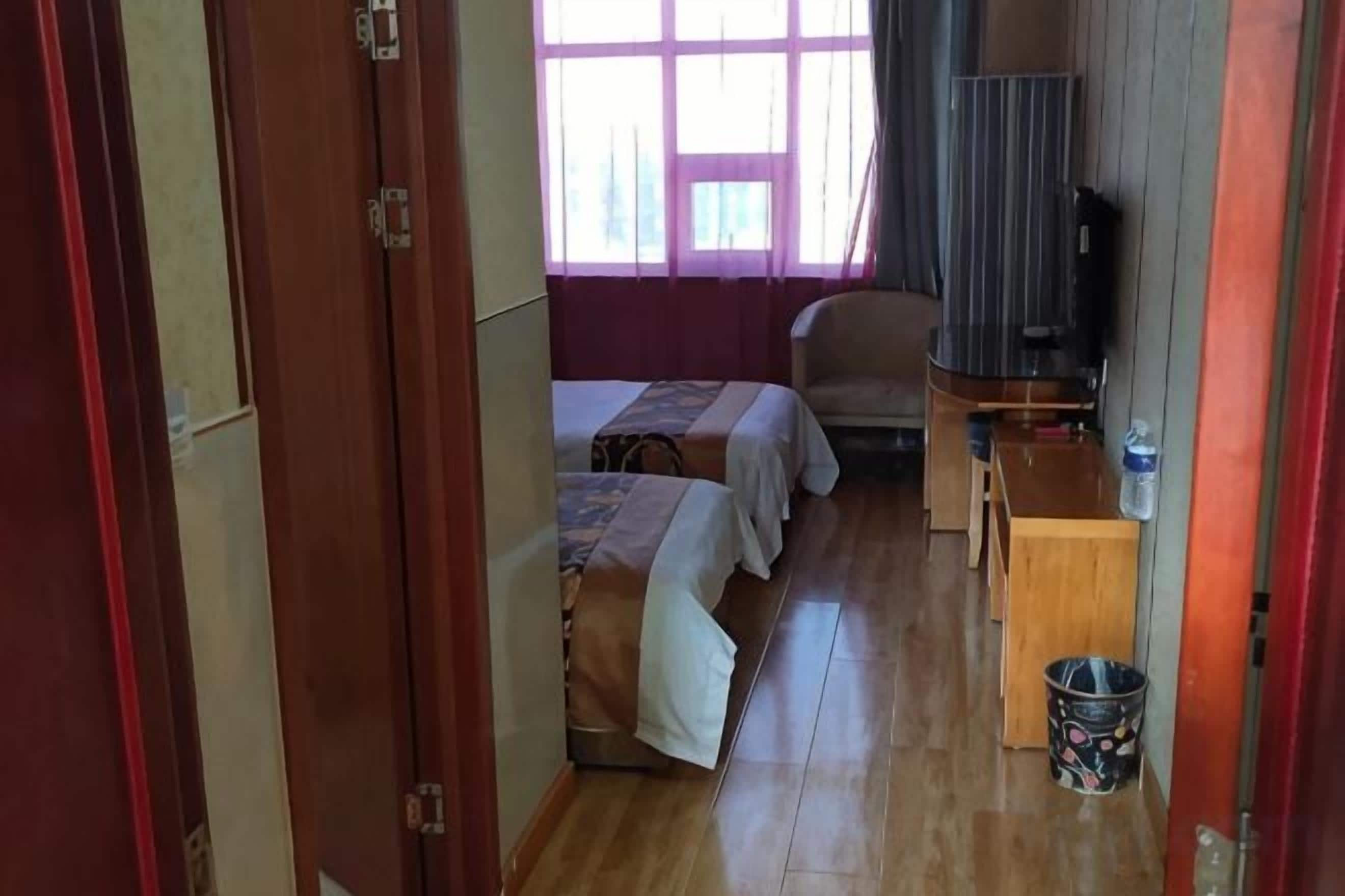 A room with two beds, a desk, a chair, and a television.