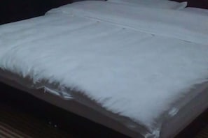 Ein Bett mit weißer Bettwäsche und einem hölzernen Kopfteil.