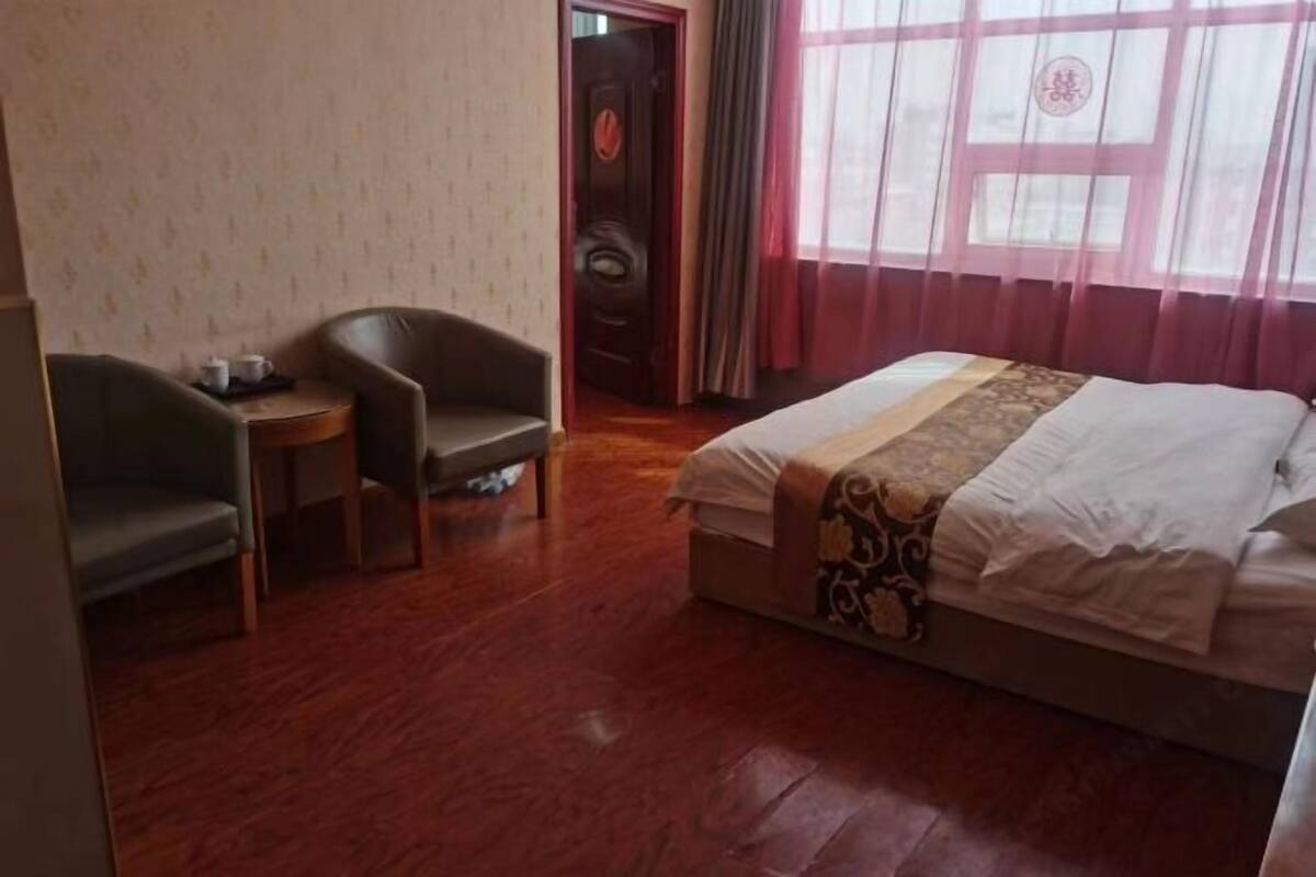 Una habitación de hotel con cama, escritorio, dos sillas y una puerta.