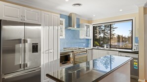 Una cocina moderna con electrodomésticos de acero inoxidable, una isla grande y vistas a los árboles por la ventana.