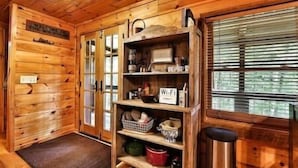 A wooden interior with a shelf unit containing kitchenware, a sign reading "Wi-Fi," and a window with blinds. - Immersive Forest Experience (Ellijay)