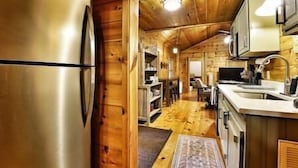 A wooden cabin interior with a kitchen area, including a refrigerator, microwave, and sink. - Immersive Forest Experience (Ellijay)