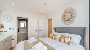 Ein Hotelzimmer mit einem Bett, einem Nachttisch, einem Spiegel und einer Uhr.