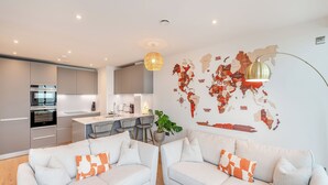 Eine moderne Wohnung mit Küche, zwei Sofas, einer Weltkarte an der Wand und einer Pendelleuchte.
