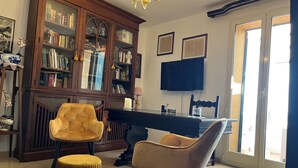 A living room with a wooden bookcase, two chairs, a desk, and a television.