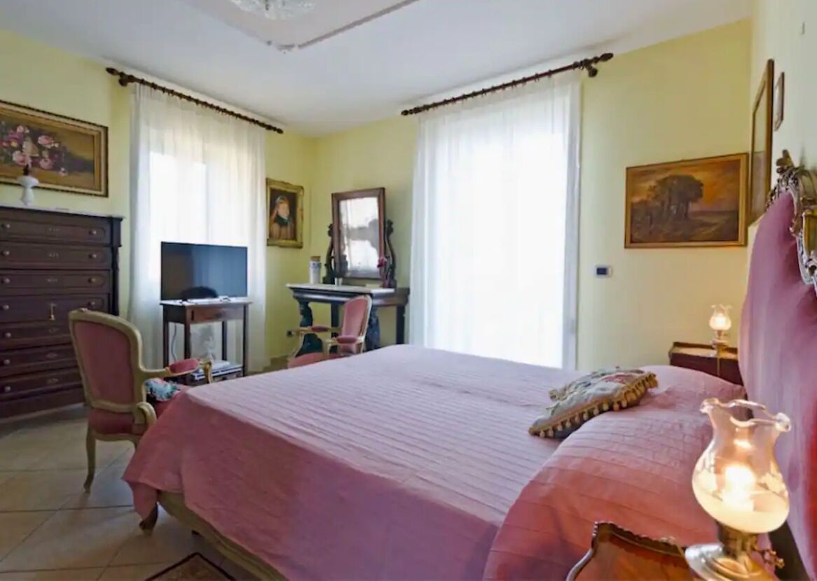 Un dormitorio con una cama grande, un escritorio con silla, un televisor y un aparador.
