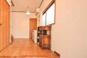 A hallway with wooden flooring, a wooden cabinet, and a ceiling light fixture. - GLOCE Mobility Guest House MIYAGASE (Kiyokawa)