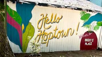 En färgstark väggmålning med texten ”Hej Hopetown!” och en skylt som lyder: ”Välkommen till BECKY’S PLACE”.