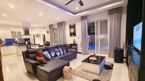 A modern living room with a dark leather sofa, a coffee table, and a flat-screen TV. - Wan D Villa Pattaya (Pattaya)