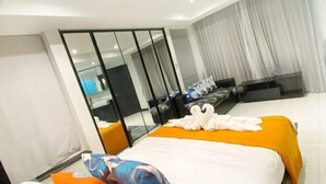 A hotel room with two beds, a wardrobe, a mirror, and a view of the city. - Wan D Villa Pattaya (Pattaya)