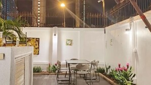 A patio area with a table and chairs, surrounded by potted plants and flowers. - Wan D Villa Pattaya (Pattaya)