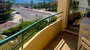 Een balkon met uitzicht op een jachthaven en palmbomen.