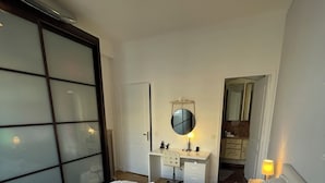 Een slaapkamer met een groot bed, een bureau, een spiegel en een kledingkast.