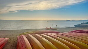 Een strand met boten en een rustige zee.