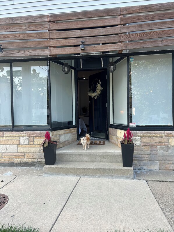 A house with a stone facade, a wooden front porch, and two potted plants.