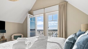 Un dormitorio con una cama grande, vistas al mar y un balcón.