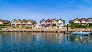 Una hilera de casas coloridas junto a un lago tranquilo con un muelle y un bote.