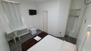 A hotel room with a bed, a desk, a chair, a TV, and a shower area. - B E B (Macapa)