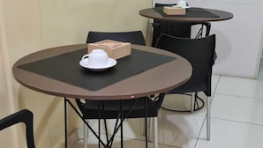 Egy kis, tiszta szoba, melyben két kerek asztal és négy fekete szék található. Mindegyik asztalon van egy fehér teáskanna és egy doboz. A szobában fehér csempézett padló és egy egyszerű, dísztelen fal van.