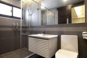 Un baño moderno con ducha, lavamanos e inodoro.