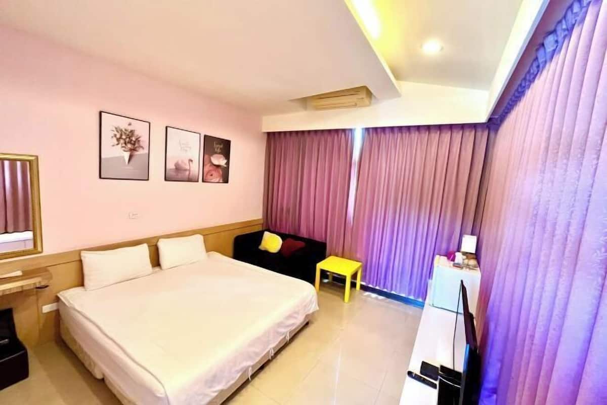 A hotel room with a bed, a small table, a sofa, and a television.