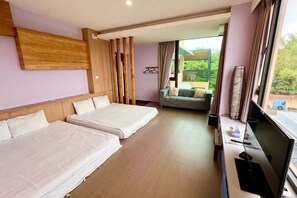 Habitación de hotel con dos camas, televisión, escritorio y vistas al exterior.