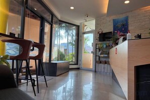 Un vestíbulo de hotel moderno con mostrador de recepción, zona de estar y ventanas amplias.