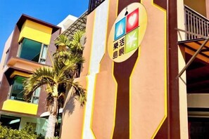 A multi-story building with a prominent sign featuring a heart and a wind turbine symbol, suggesting a focus on health and sustainability. - Lohas Island B&B (Pingtung)