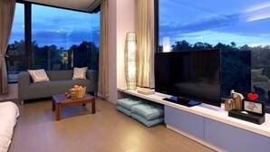 Un soggiorno moderno con un divano, un tavolino, una TV e un'ampia finestra che offre vista all'esterno.