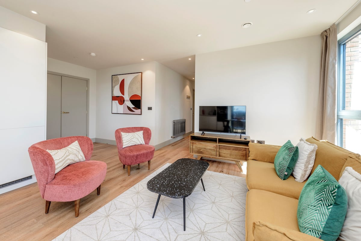 A modern living room with a sofa, two armchairs, a coffee table, and a television.