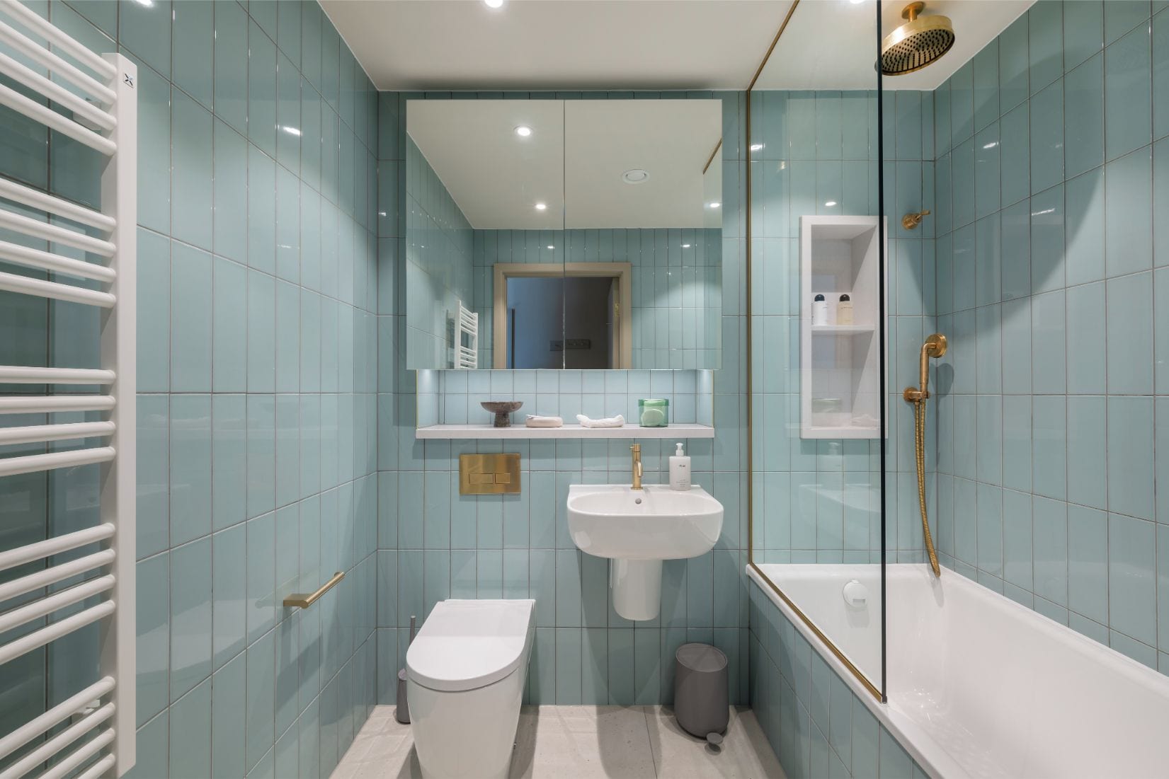 Un baño moderno con ducha cubierta por vidrio, un lavamanos blanco y un inodoro.
