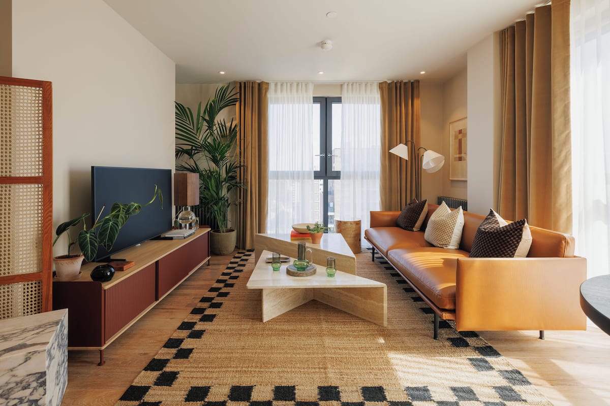 A modern living room with a sofa, coffee table, TV, and potted plants.