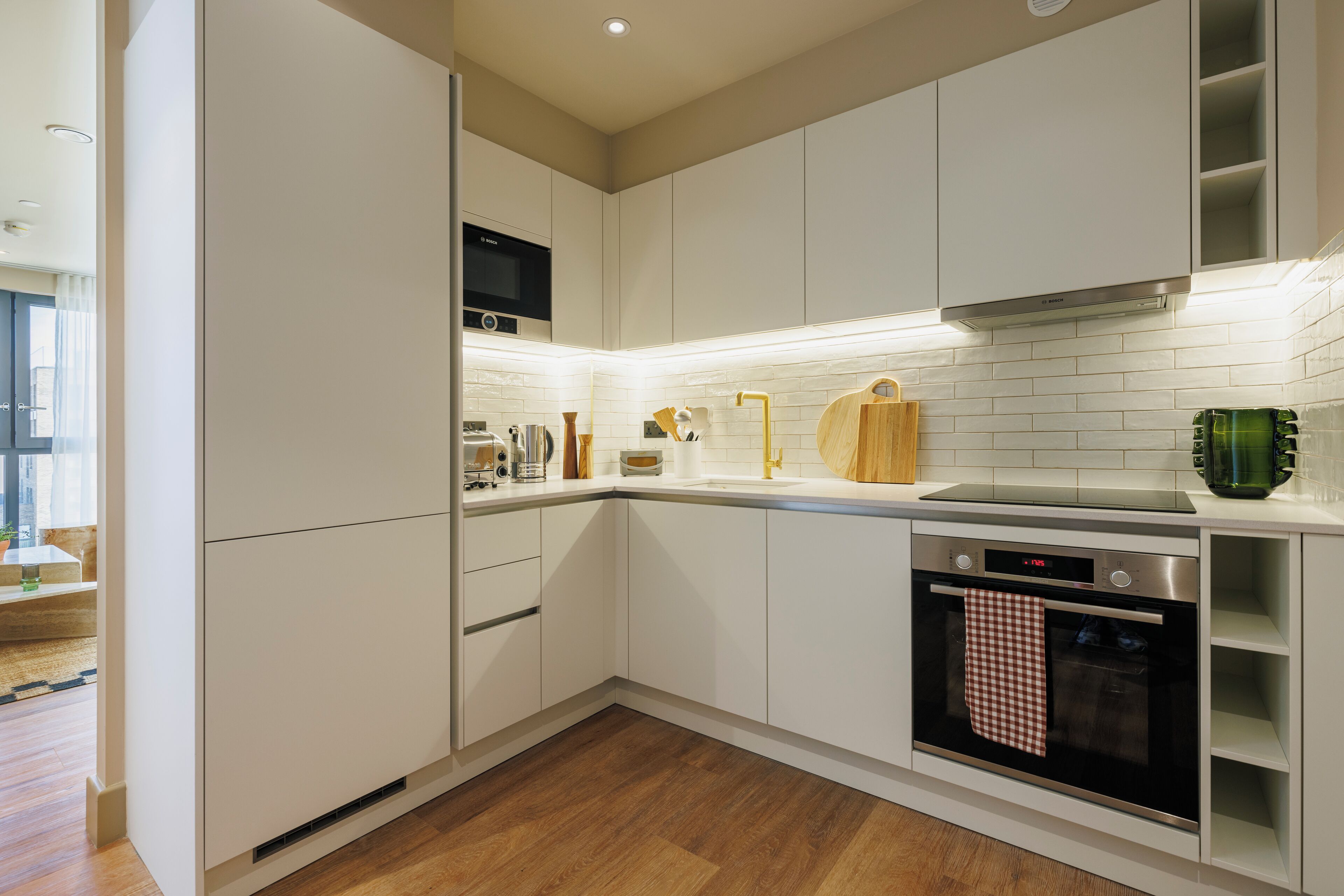 A modern kitchen with white cabinets, a built-in oven, and a microwave.