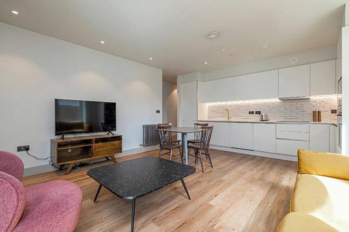 A modern living room with a flat-screen TV, a black coffee table, and a sofa.