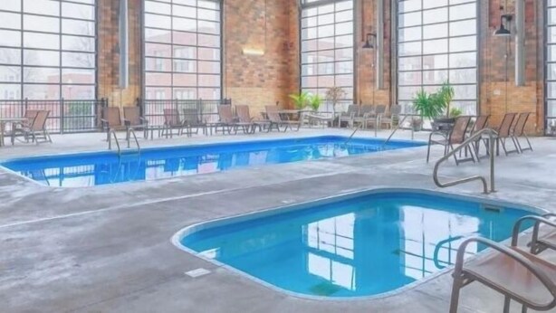 Une piscine intérieure dotée de plusieurs couloirs, entourée de murs en briques et de grandes fenêtres.